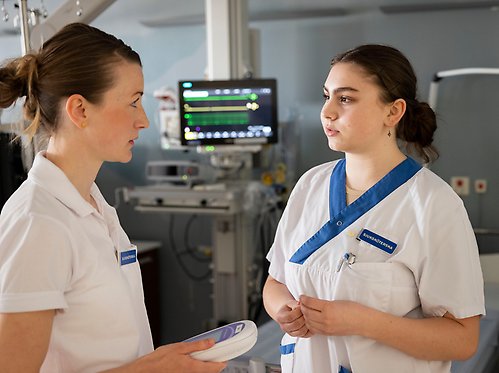 Two nurses in front of a monitor.